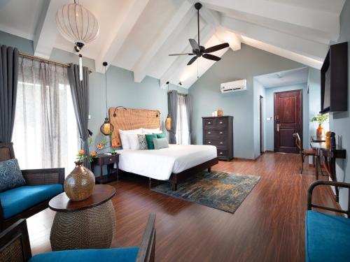 a bedroom with a bed and a living room at AIRA Boutique Hoi An Hotel & Villa in Hoi An
