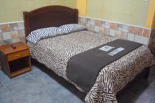 a bed with a black and white comforter and a table at Hostal La Casa De Rodrigo in Baeza