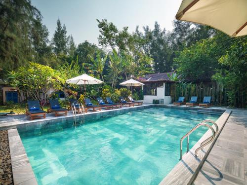 a large swimming pool with chairs and umbrellas at AIRA Boutique Hoi An Hotel & Villa in Hoi An