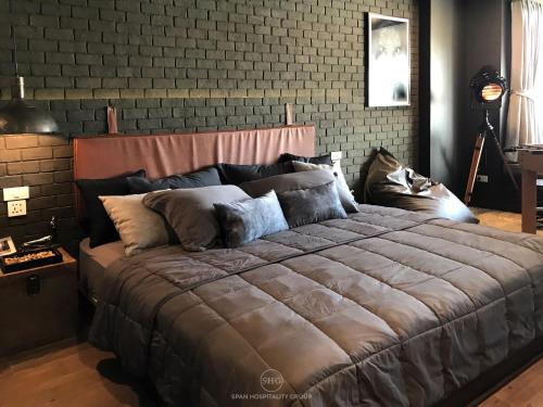 a large bed in a room with a brick wall at Stay in Style at Nimman R911 in Chiang Mai