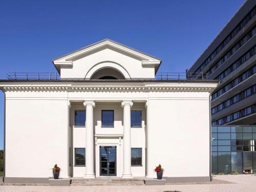 a white building with a tower on top of it at Aurora Hotel Klaipeda in Klaipėda