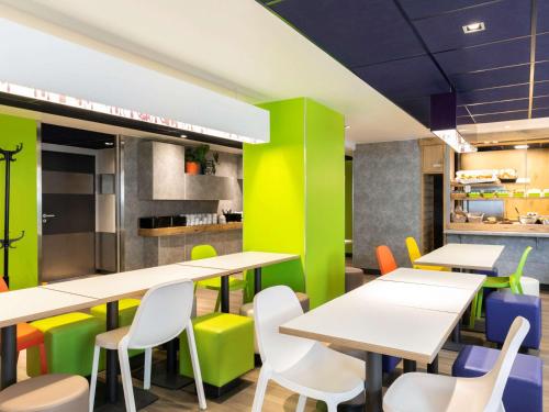 a cafeteria with white tables and colorful chairs at ibis budget Meudon Paris Ouest in Meudon