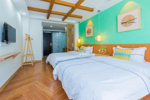 two beds in a room with green walls and a television at Tongli Slowlife River View Inn in Suzhou