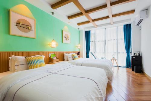 two beds in a room with green walls at Tongli Slowlife River View Inn in Suzhou