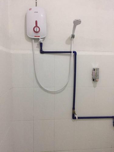 a shower in a bathroom with a hose on the wall at Bunga Raya Guest House BALING in Baling