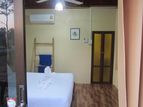 a bedroom with a white bed and a door at Baan Thung Home Stay in Prasat