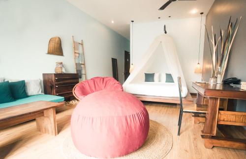 a living room with a pink chair and a bed at iRoHa Garden Hotel & Resort in Phnom Penh