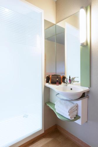 une salle de bain avec un lavabo et un miroir dans l'établissement ibis budget Cabourg Dives sur Mer, à Dives-sur-Mer
