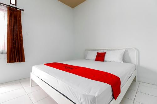 a bedroom with a white bed with a red blanket at RedDoorz @ Jagakarsa 2 in Jakarta