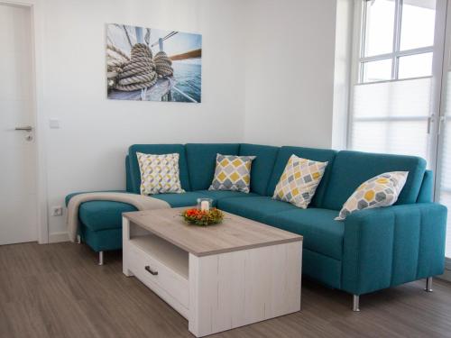 a living room with a blue couch and a coffee table at Fewo Strandleben Haus Strandperle in Börgerende-Rethwisch