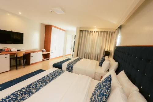 a hotel room with two beds and a desk at The Madeline Boutique Hotel & Suites in Davao City