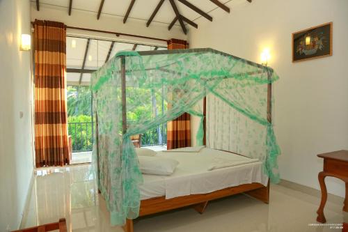 een slaapkamer met een hemelbed en een raam bij Lake Edge Holiday Inn in Tissamaharama