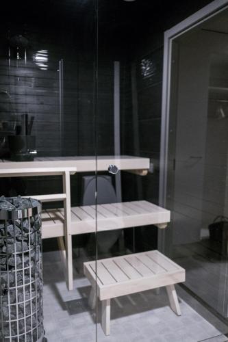 a glass shower with a bench and a table at Santasport Apartment Hotel in Rovaniemi