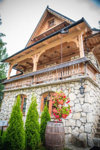 a large stone house with a tree at Rezydencja Sąsiadów Zakopanego in Zakopane