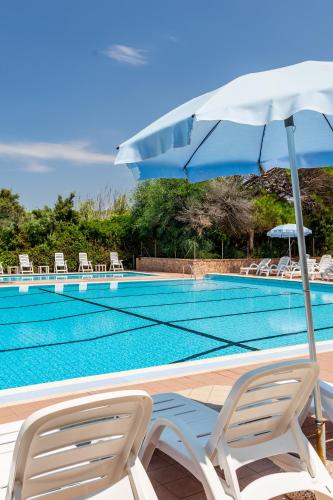 a swimming pool with two chairs and an umbrella at Club Hotel Residence Baiaverde in Valledoria