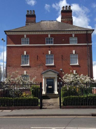 a red brick building with a gate in front of it at Historic Peel House Serviced Apartments in Burton upon Trent