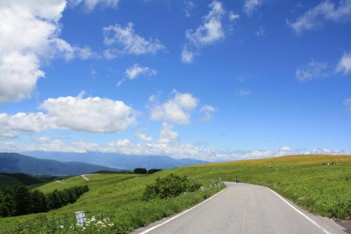 a road on the side of a green hill with a blue sky at Sky Park Hotel in Chino