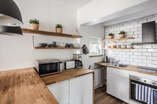 eine Küche mit weißen Schränken und einer Mikrowelle in der Unterkunft Haave Apartments in Valkeakoski