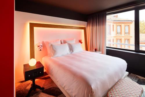 a bedroom with a large white bed with a window at Mama Shelter Toulouse in Toulouse