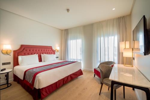 Habitación de hotel con cama y escritorio en Eurostars Azahar en Córdoba
