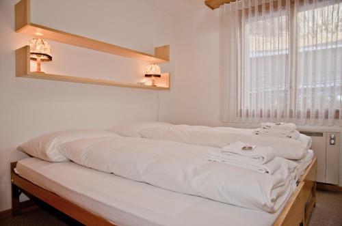 a bed with white sheets on it in a room at Apartment Grindelwaldgletscher - GRIWA RENT AG in Grindelwald