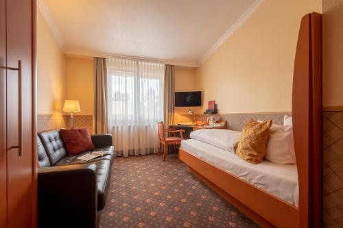 a hotel room with a bed and a couch and a desk at Hotel Wegner - T h e culinary art hotel in Hannover