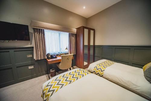ゲーンズボロにあるThonock Park B&Bのベッド2台、デスク、テレビが備わるホテルルームです。