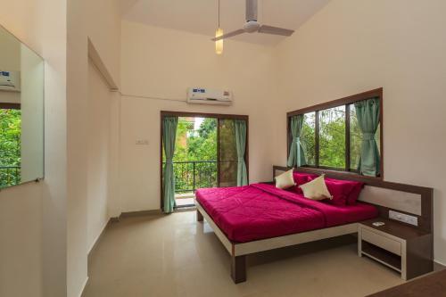 um quarto com uma cama com lençóis vermelhos e uma janela em SaffronStays Ekaant, Vikramgad - party-perfect pool villa with spacious lawn em Pālghar