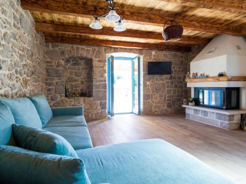 een woonkamer met een blauwe bank en een stenen muur bij Gorgeous villa in Malinska with private pool in Malinska