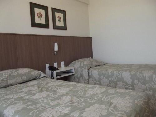 a hotel room with two beds and a table at L'Hirondelle Flat Service in Campinas