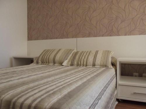a bedroom with a bed with a painting on the wall at L'Hirondelle Flat Service in Campinas
