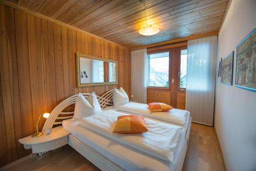 two beds in a room with wooden walls and wooden floors at Casa Serena in Arosa