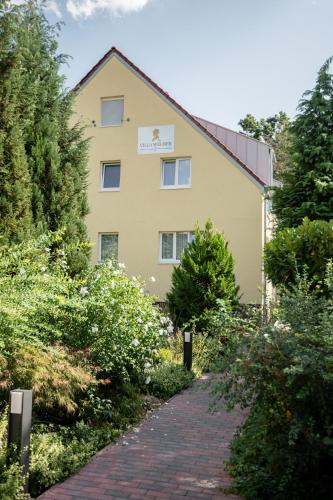 a yellow building with a brick path in front of it at Hotel Wegner - T h e culinary art hotel in Hannover