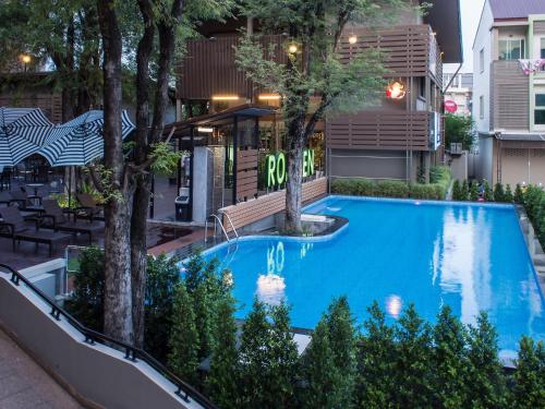 una piscina con árboles frente a un edificio en Romyen Garden Place en Nakhon Ratchasima