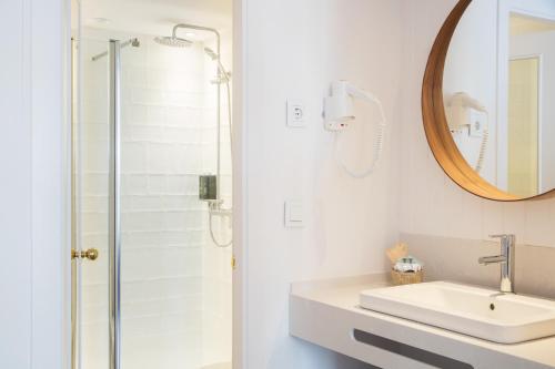 a white bathroom with a sink and a shower at The 15th Boutique Hotel by Bondia Group in Lloret de Mar