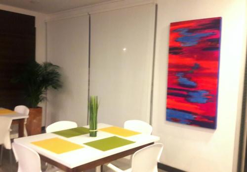 a dining room with a white table and a painting at Hotel Rosales Plaza in Manizales