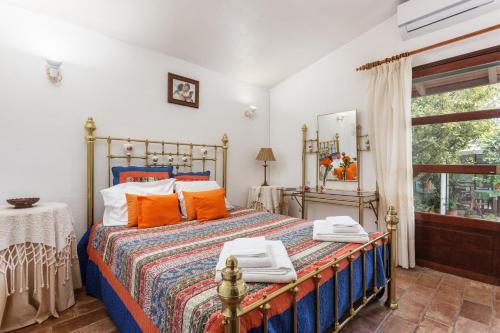 カバナス・デ・タビラにあるTypical Algarvian Family Homeのベッドルーム1室(オレンジ色の枕と窓付)