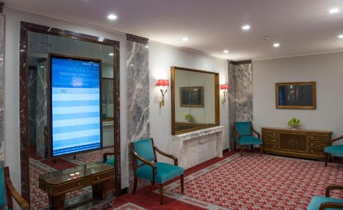 a large screen in a waiting room with chairs at Bettoja Hotel Mediterraneo in Rome