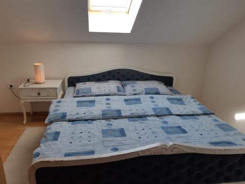 a bedroom with a bed with a blue comforter and a window at Apartman Kupres Centar in Kupres