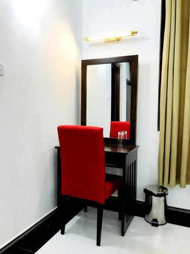 a desk with a red chair and a mirror at Siluni's Villa in Anuradhapura