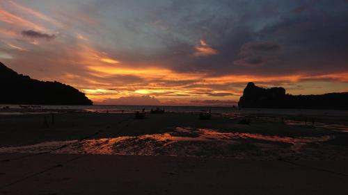 a sunset on a beach with a rock in the distance at Blanco Central in Phi Phi Don