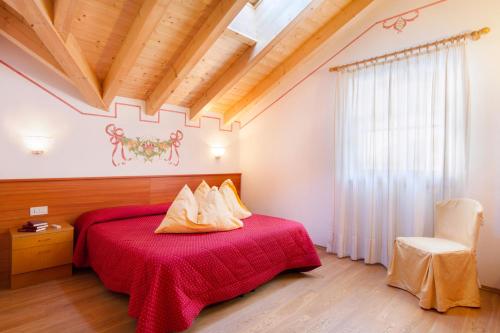 a bedroom with a red bed and a chair at Casa Nonni in Molveno