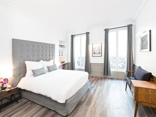 パリにあるLivinParis - Luxury 3 & 4 Bedrooms Montmartre Iのベッドルーム1室(大型ベッド1台、窓2つ付)