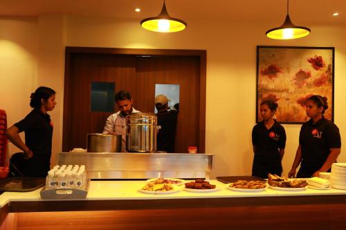 a group of people standing around a counter with food at Aura One Hotel in Cochin