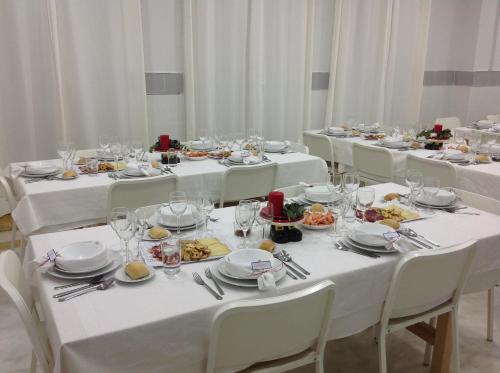 Colegio Mayor Careu - Women Only - University Community في إشبيلية: مجموعة من الطاولات مع مفارش المائدة البيضاء وأطباق الطعام