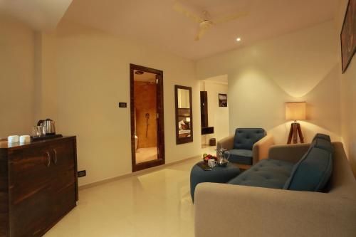 a living room with a couch and two chairs and a mirror at Aura One Hotel in Cochin
