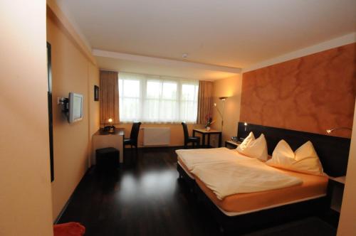 ein Hotelzimmer mit einem Bett, einem Tisch und Stühlen in der Unterkunft Gasthof Bacher in Villach