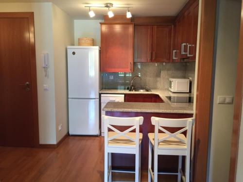 a kitchen with a white refrigerator and two bar stools at Apartamento frente Pistas de Esquí La Molina in La Molina