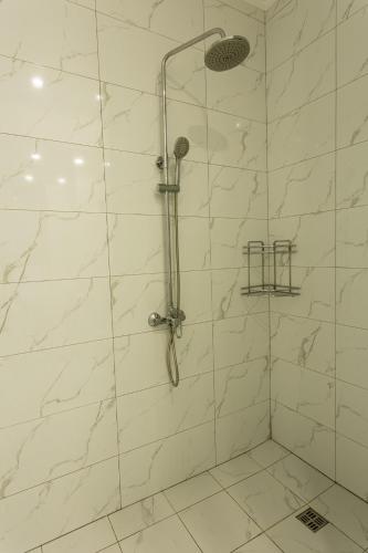 a bathroom with a shower with white marble walls at Ambassador in Almaty