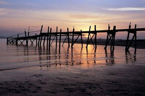 a wooden pier on the beach at sunset at Somo Garden Villas in Somo